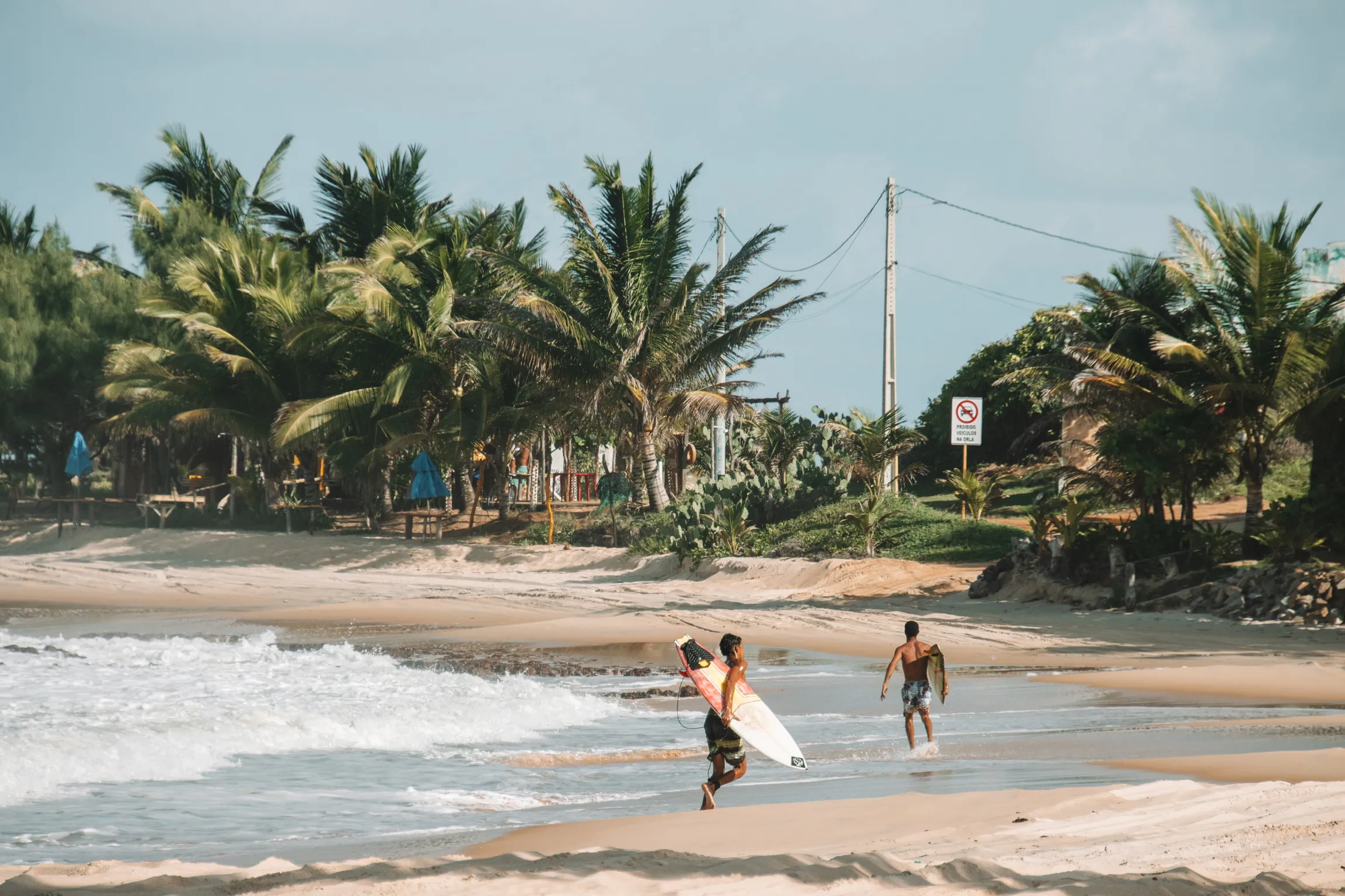 Surfer walking along the beach near Casa Basilico coliving in Brazil